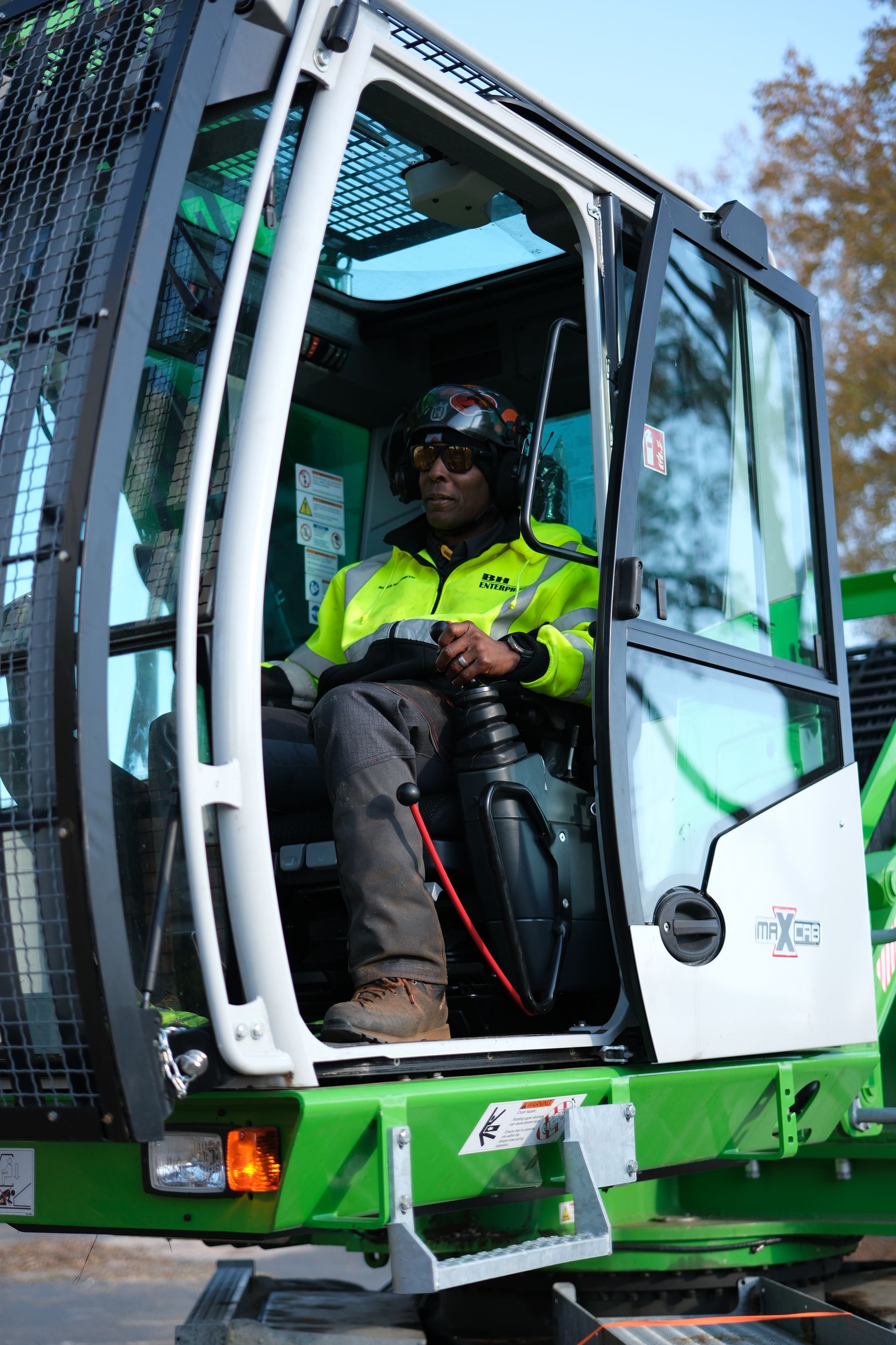 A man is sitting in the driver 's seat of a green excavator.