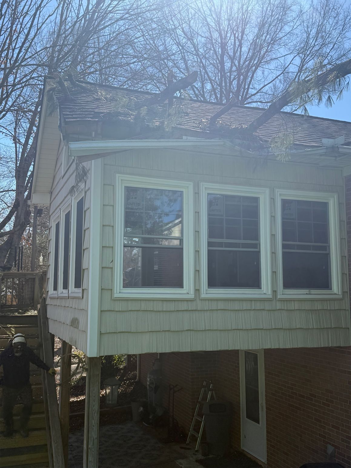 Sunroom addition on stilts with three large windows and a person on stairs.
