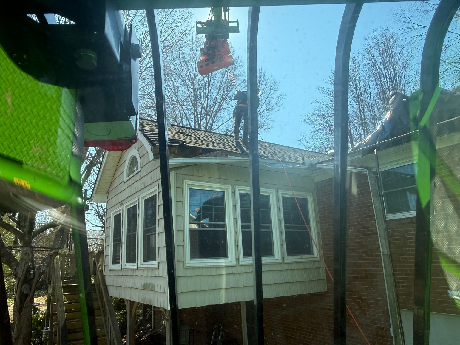 House with workers on the roof, viewed from inside of a crane.