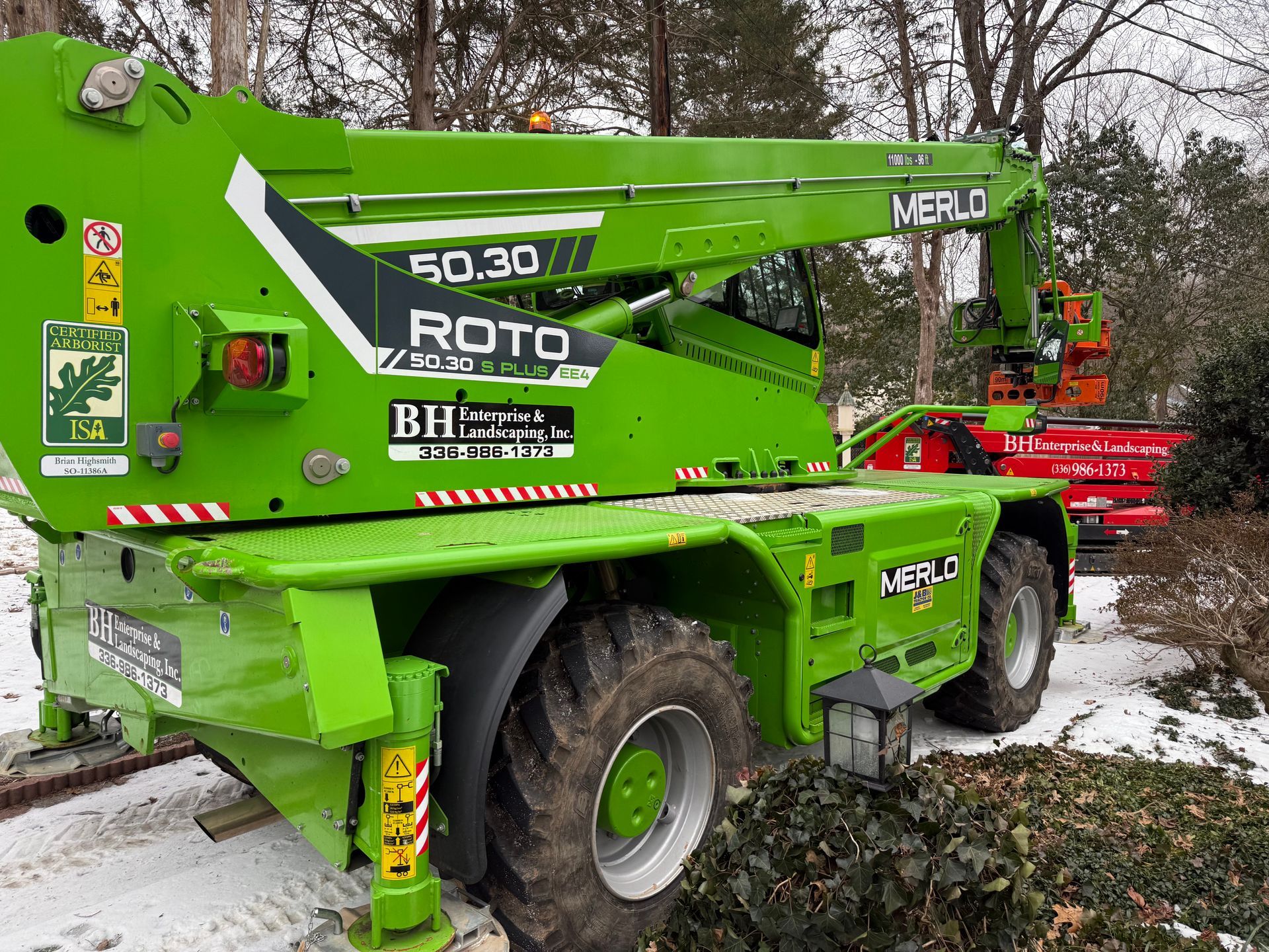 Green Merlo ROTO telehandler in a snowy outdoor setting.