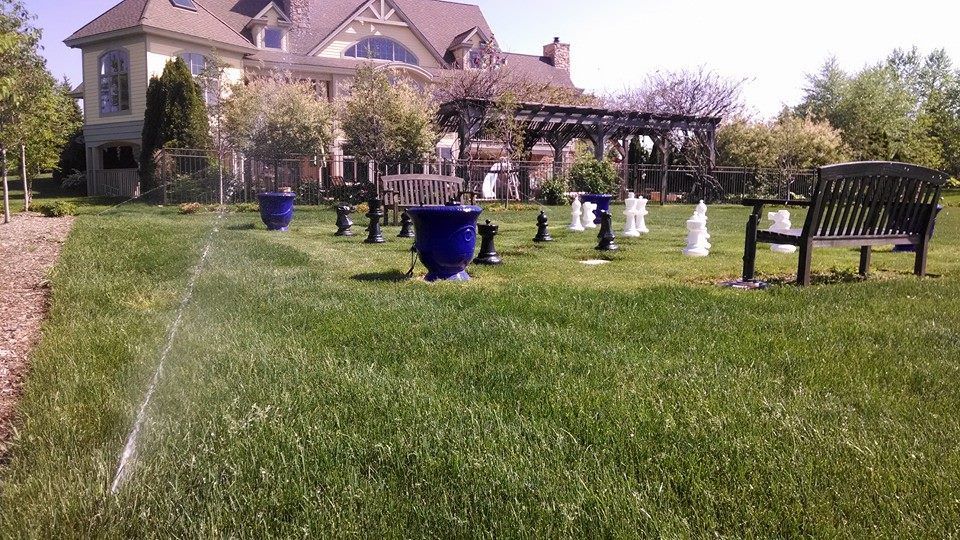 A lawn with a bench and chess pieces in front of a house