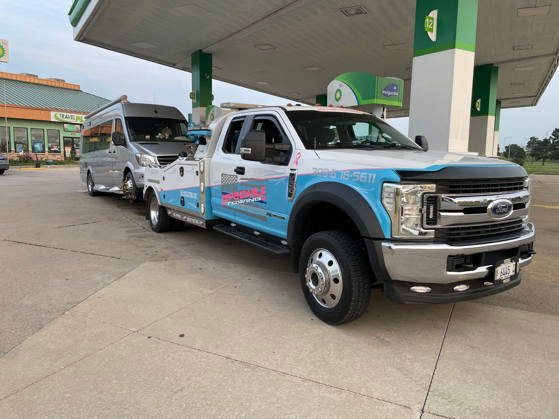 A tow truck is parked in front of a gas station.