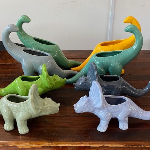 a variety of multi-colored dino plant pots