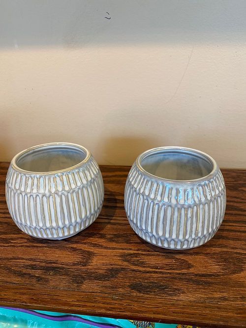 Two white vases are sitting on a wooden table.
