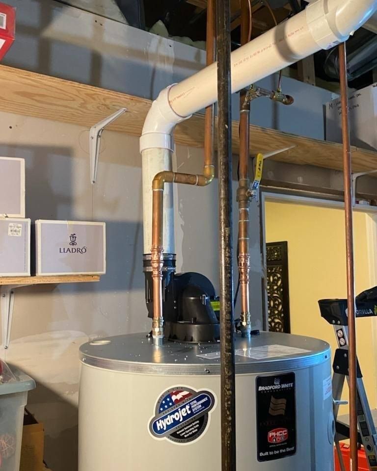 A water heater with copper pipes, vent, and an American flag sticker in a basement setting.