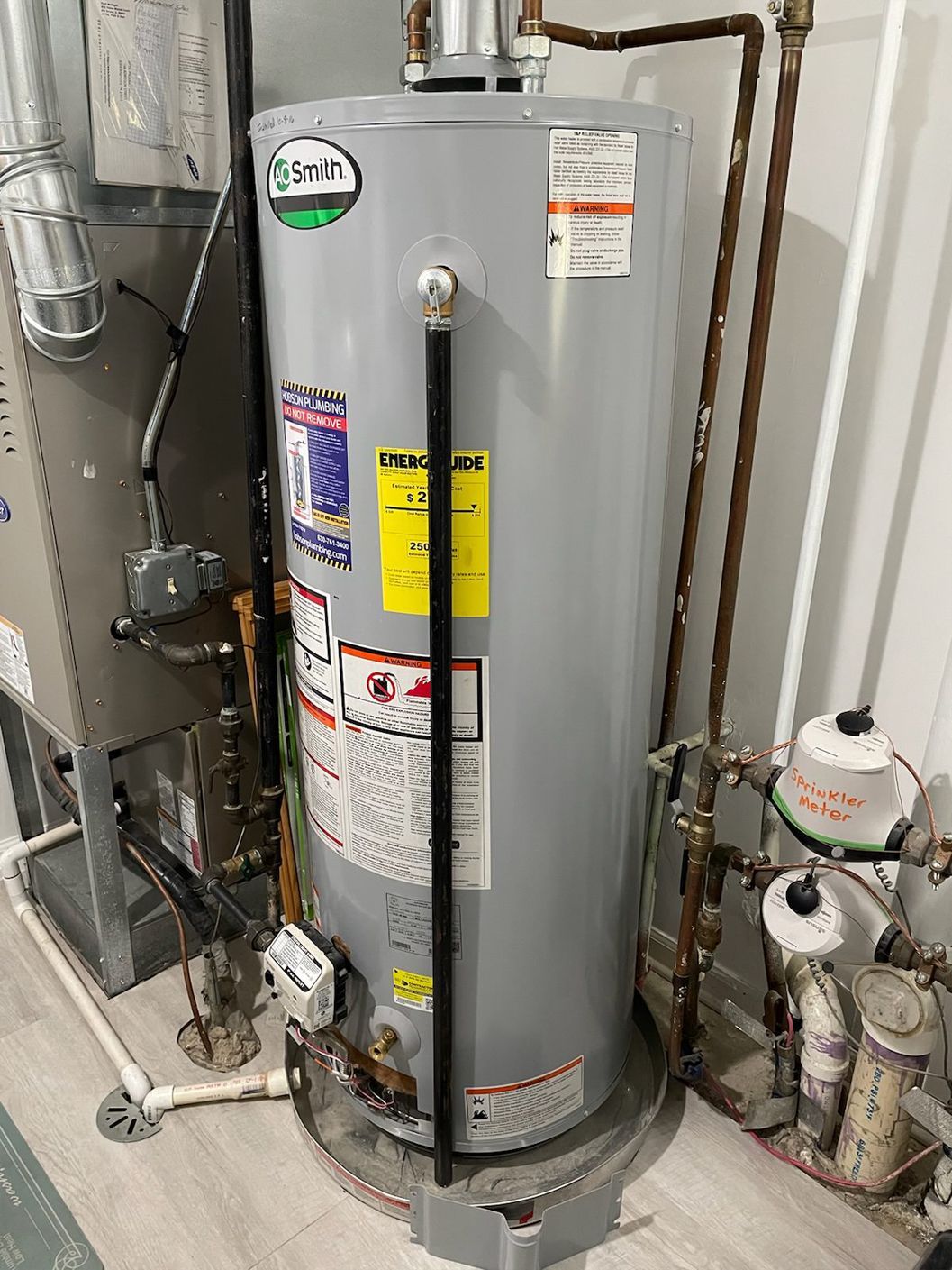 Gray water heater with attached pipes and safety labels.