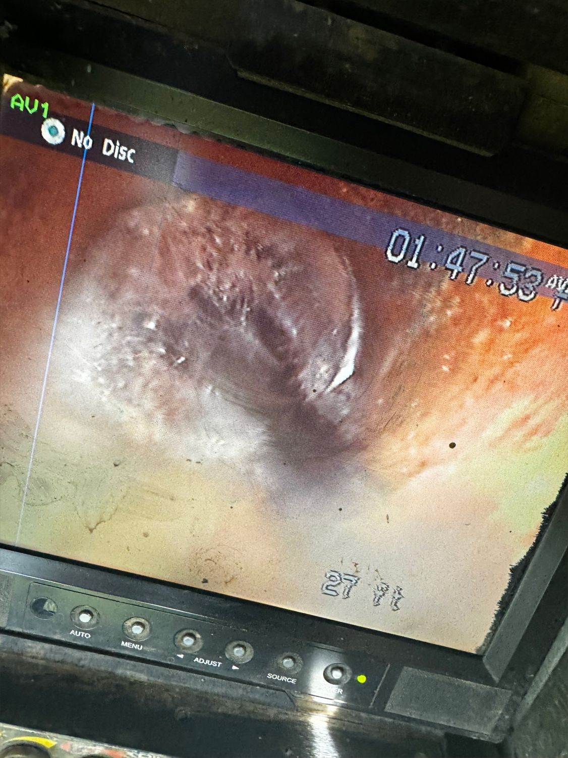 Internal view of a pipe, showing a dark, circular obstruction. The screen displays a timestamp: 01:47:52.