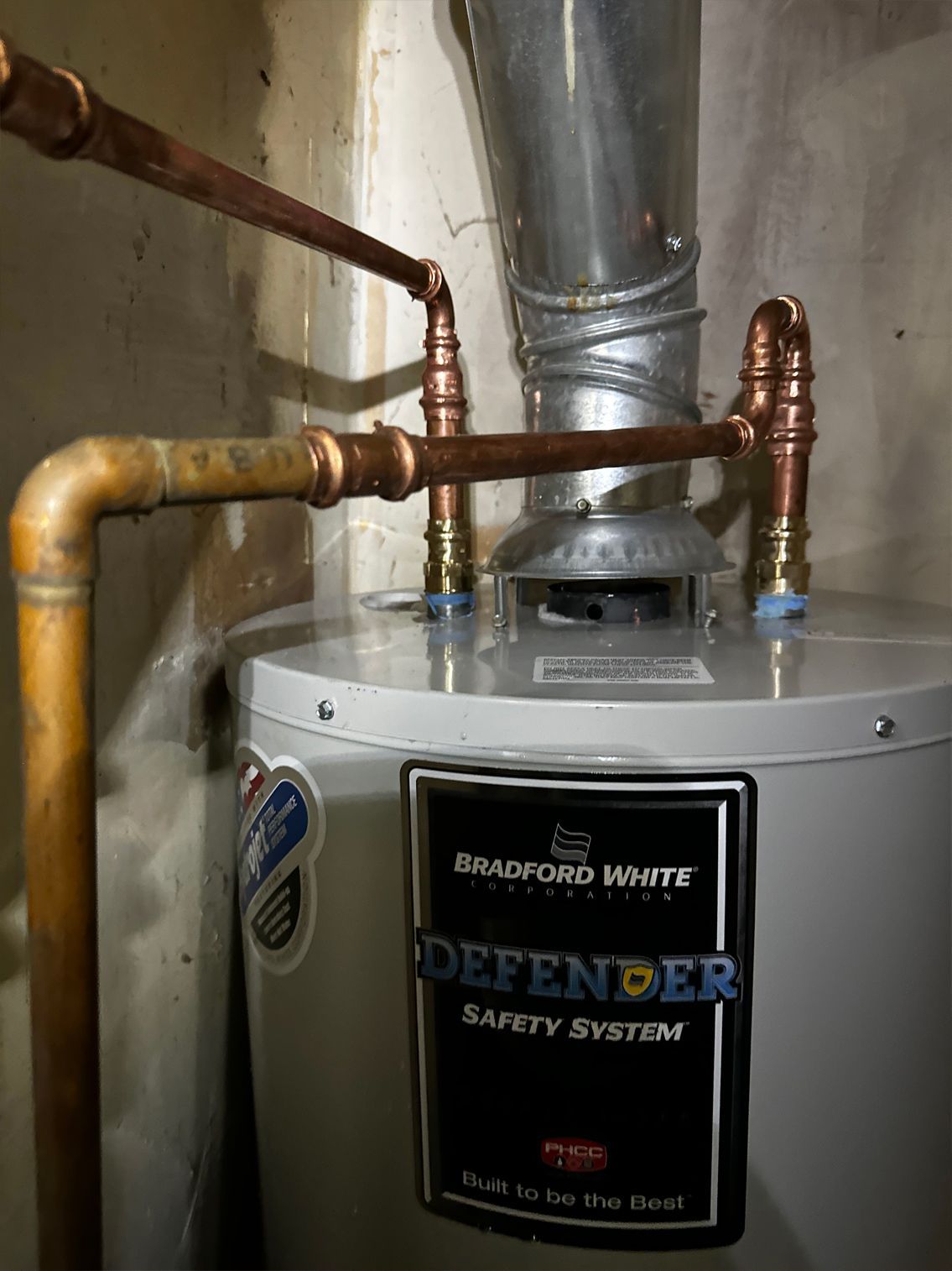 Copper pipes connected to a Bradford White water heater in a utility space.