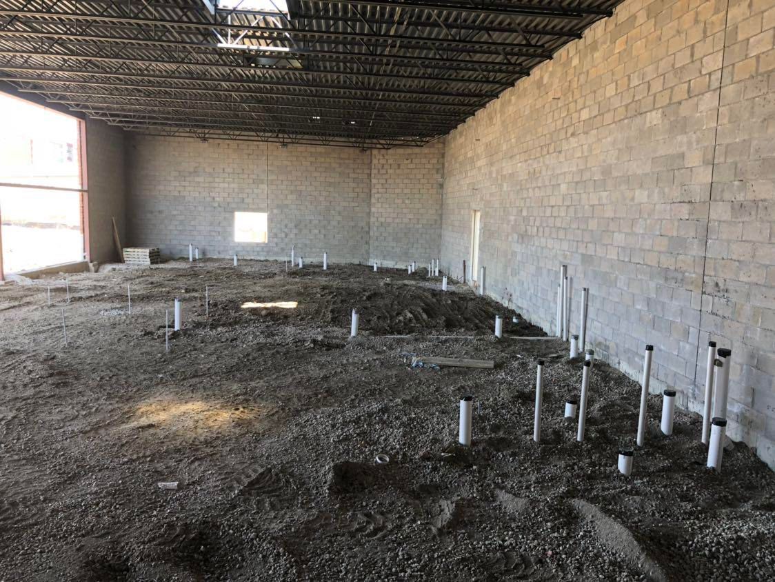 Interior of unfinished commercial space with exposed pipes and cinder block walls.