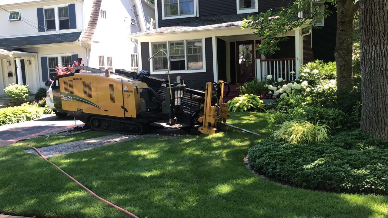 A directional drilling machine working on the lawn of a house.
