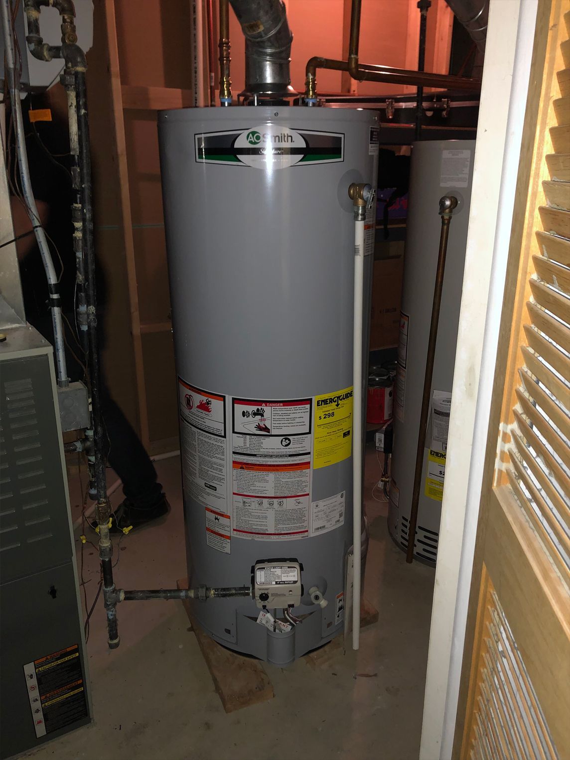 Tall gray water heater in a utility room.
