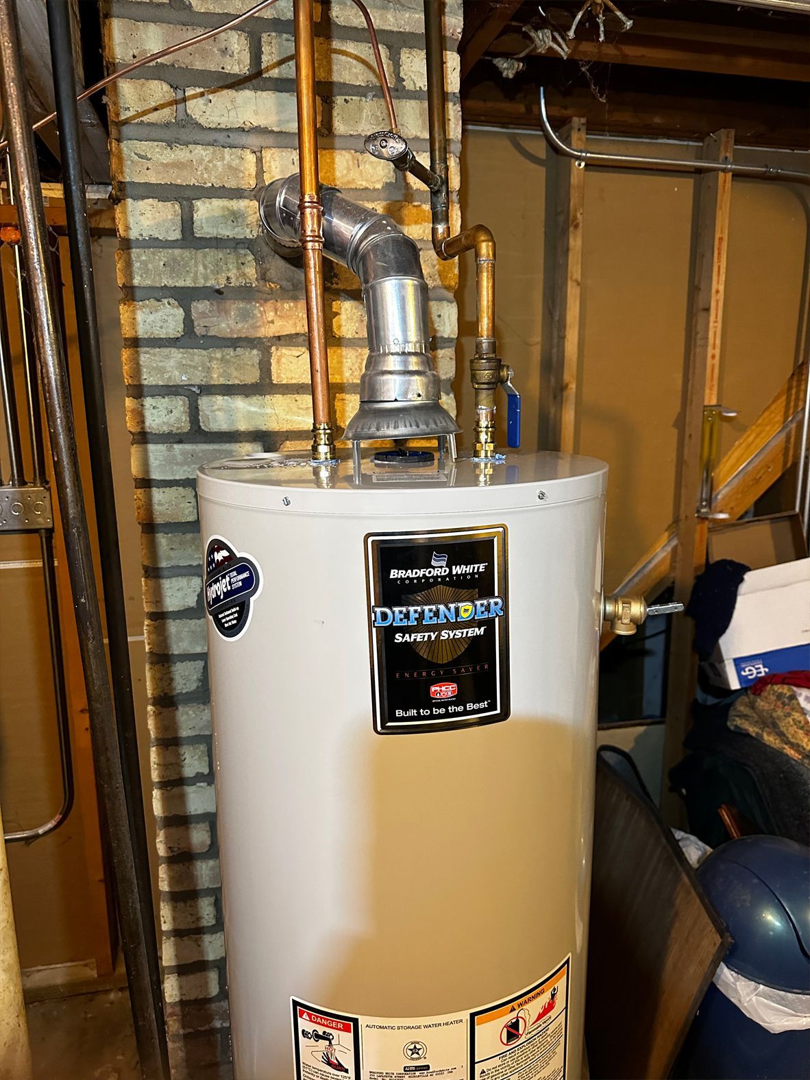A hot water heater with vent pipe in a basement setting.