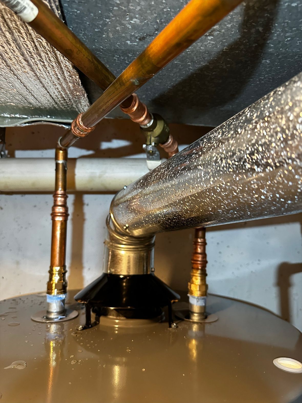 Copper pipes connected to a water heater, with insulation and fittings visible.