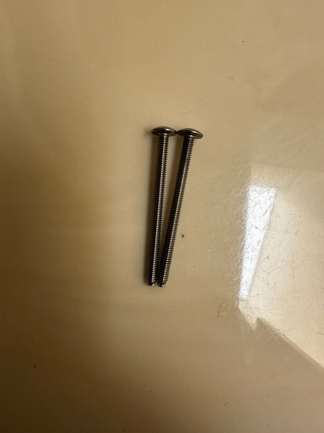 Two silver screws on a light brown surface.