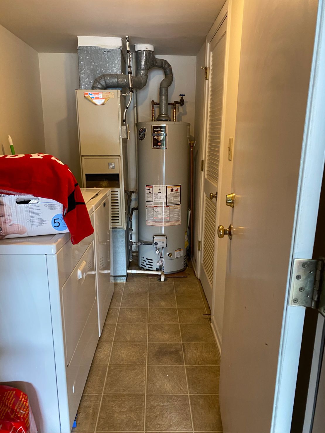 Laundry room with a washing machine, dryer, water heater, and furnace.