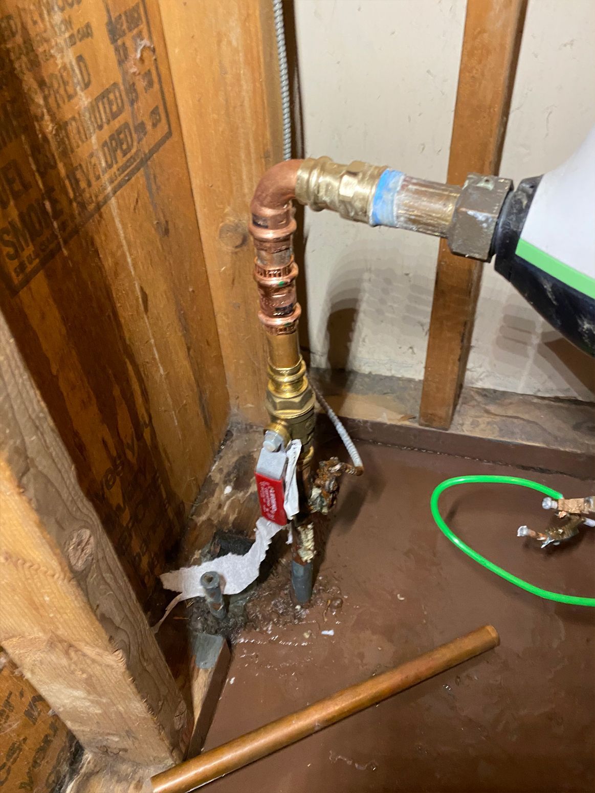 Copper plumbing pipes and valve assembly in a wooden wall cavity.