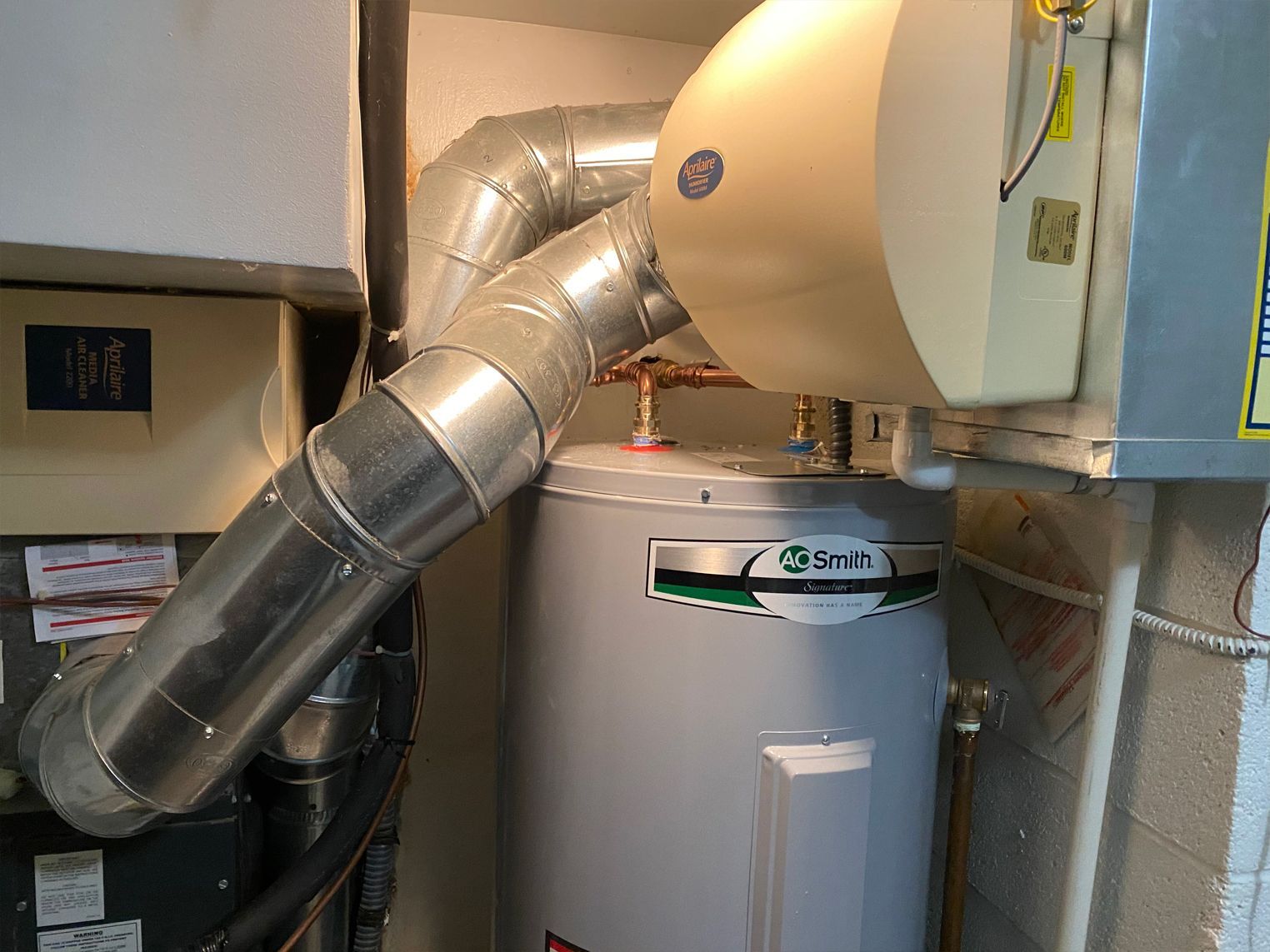 Water heater with attached ductwork and humidifier in a utility room.