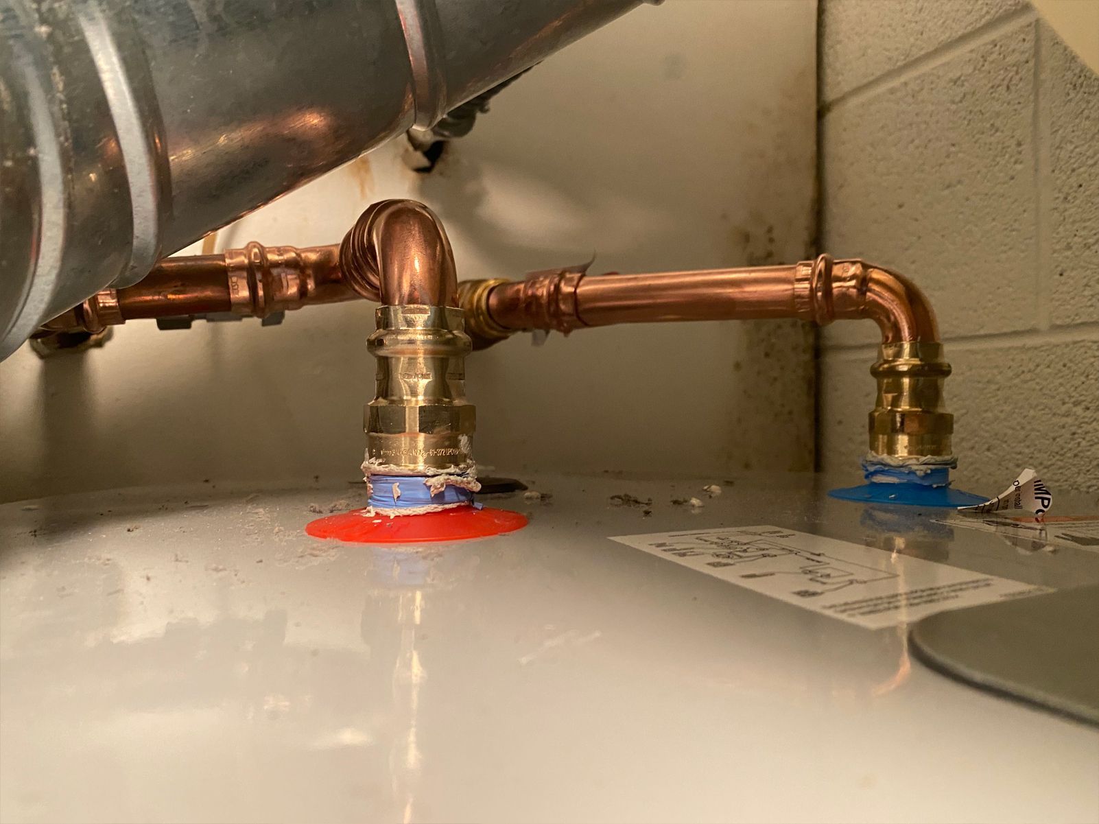 Copper pipes connected to a hot water heater; fittings are visible and blue/red discs are present.