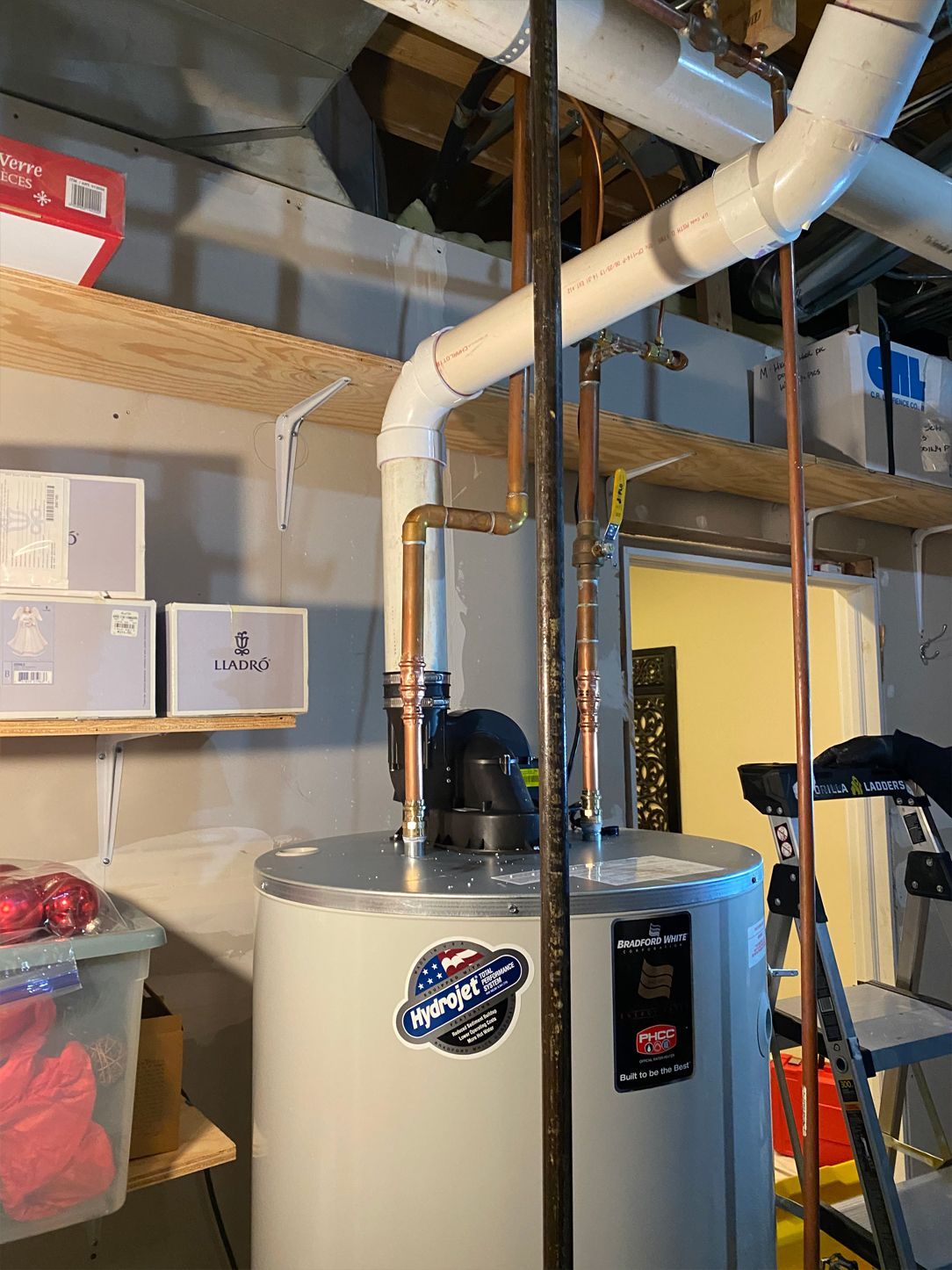 Water heater with copper pipes, white vent pipe, and storage shelves in a basement setting.