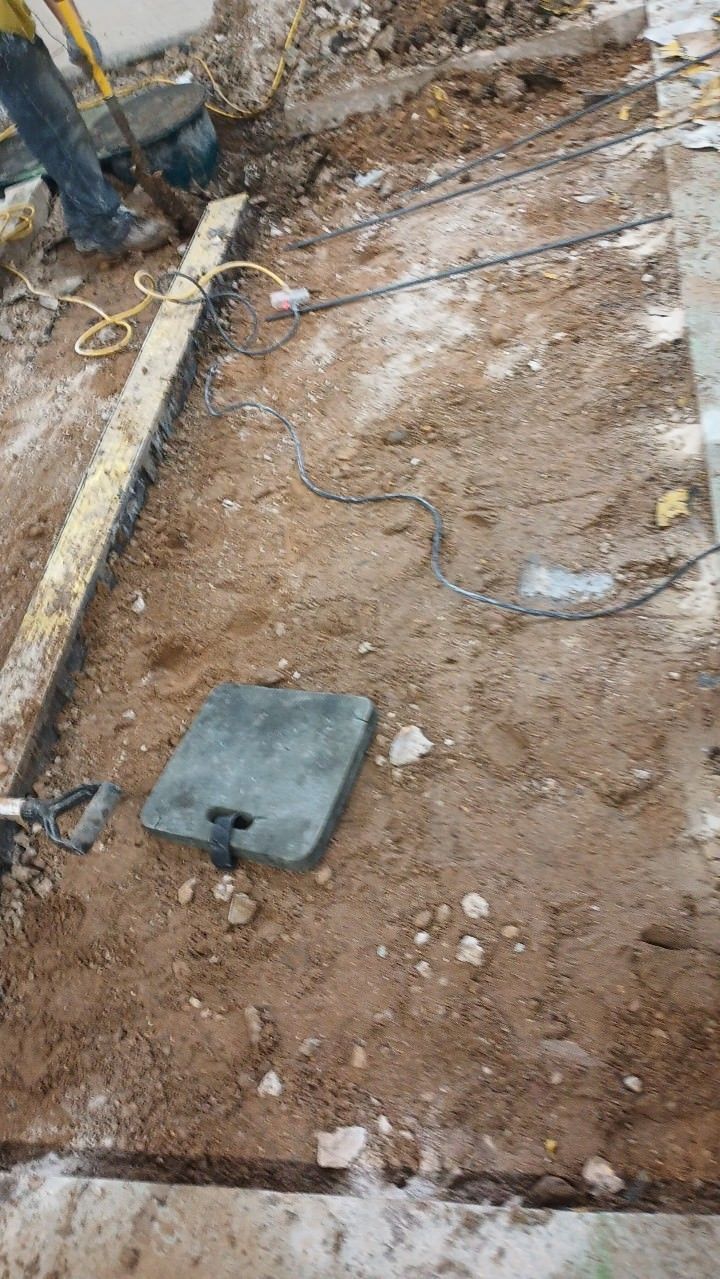 Construction site. Excavation in progress with exposed dirt, concrete and a worker.