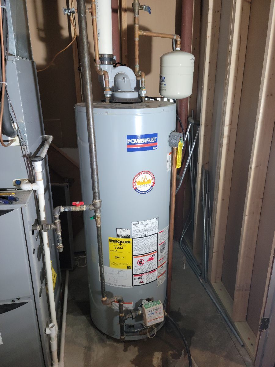 A gray Power Vent water heater in a utility room.  Nearby is a furnace and exposed wooden studs.