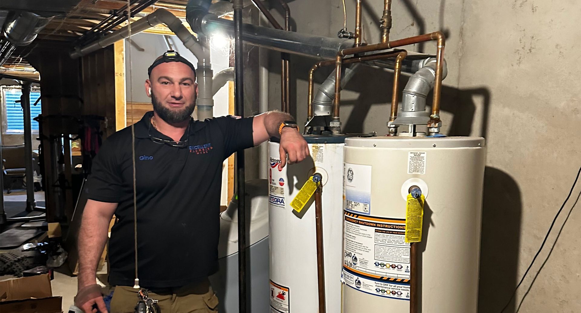 Man pointing at two water heaters in a basement.