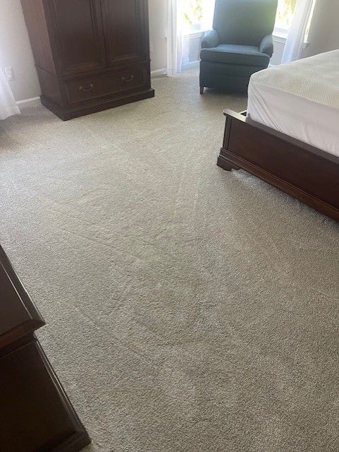 A bedroom with a bed , chair , dresser and carpet.