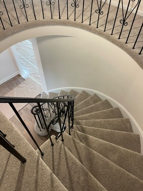 A spiral staircase with a metal railing and carpeted steps.