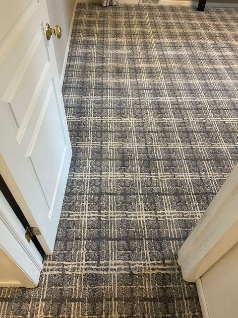 A carpeted floor with a plaid pattern in a room next to a door.
