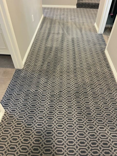 A hallway with a gray carpet and a pattern on it.