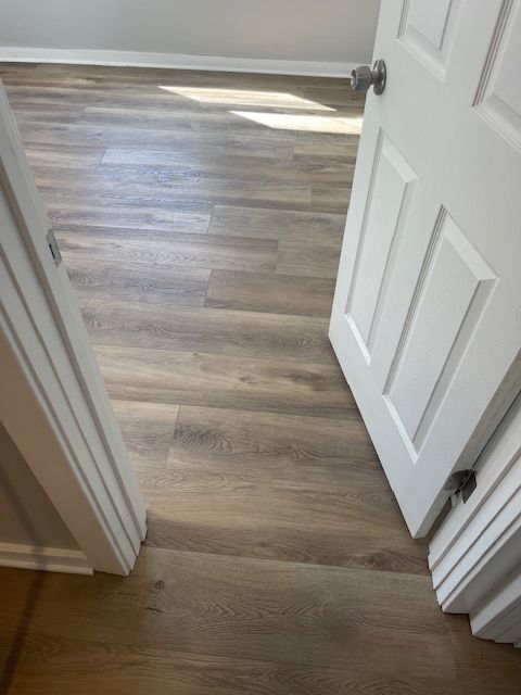 A bedroom with hardwood floors and a white door.
