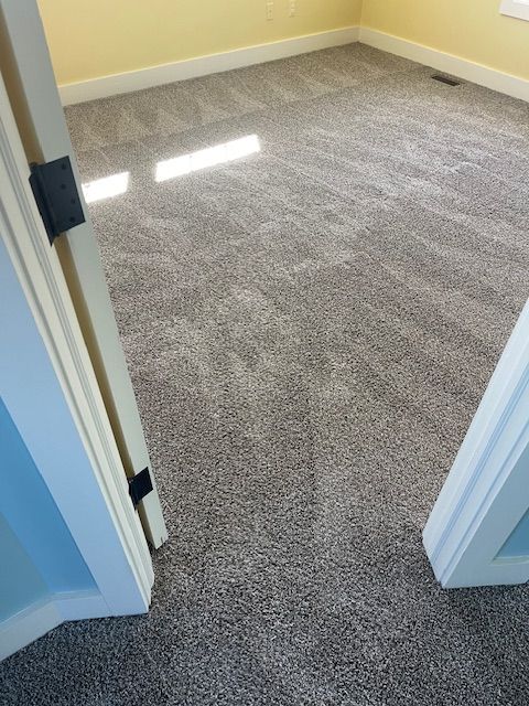 A bedroom with a carpeted floor and a doorway leading to it.