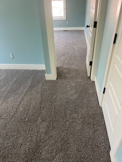 A hallway in a house with a carpeted floor and blue walls.