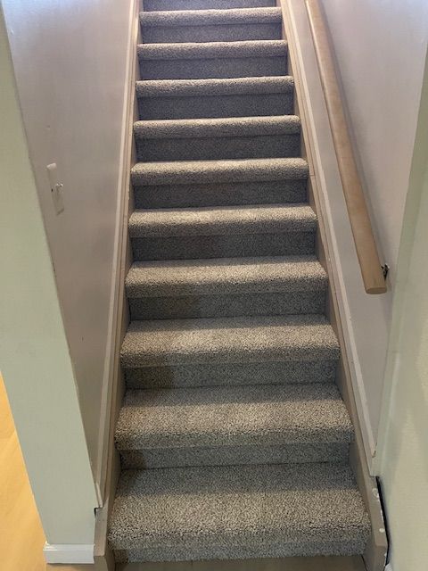 A set of stairs with carpeted steps and a wooden railing in a house.