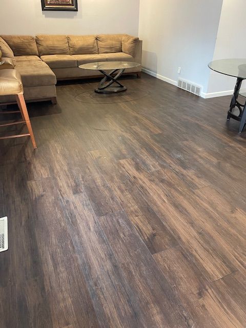 A living room with hardwood floors , a couch , a table and chairs.