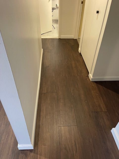 A hallway with a wooden floor and white walls.