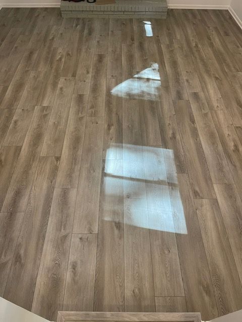 A wooden floor with a reflection of a window in it.