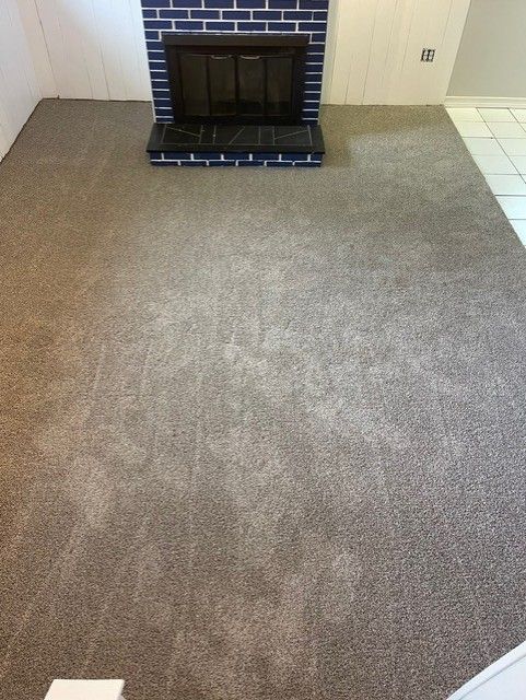 A living room with a fireplace and a carpeted floor.