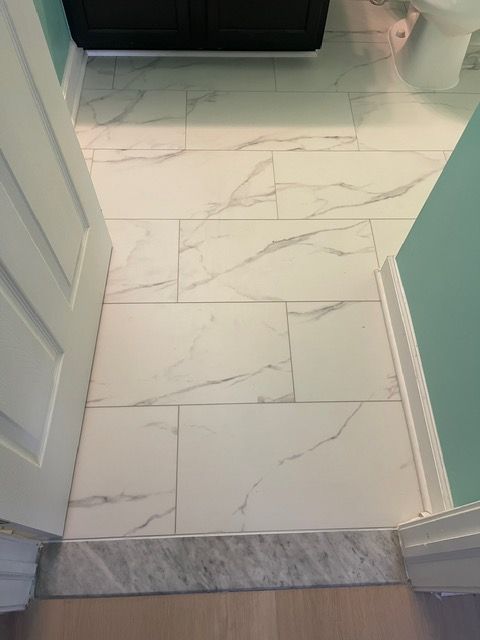 A bathroom with white tile floors and a toilet.