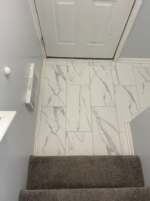 Stairs leading up to a door with marble tiles on the floor