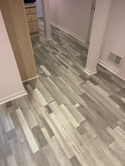 A hallway with a wooden floor and a pink wall.
