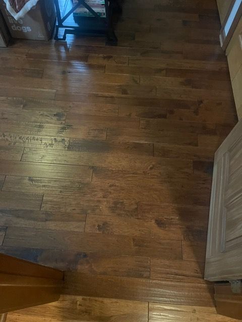 A wooden floor in a room next to a door.