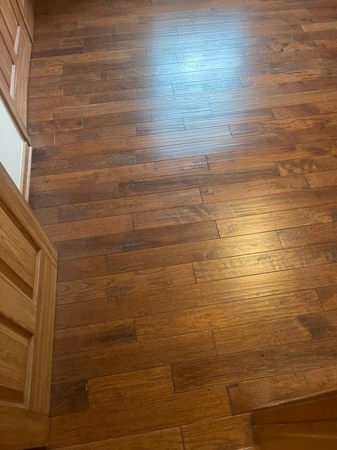 A close up of a wooden floor in a room with stairs.