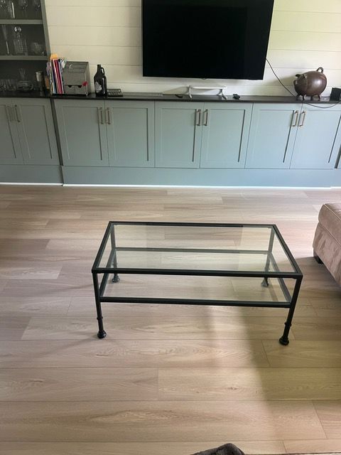 A living room with a glass coffee table and a flat screen tv.
