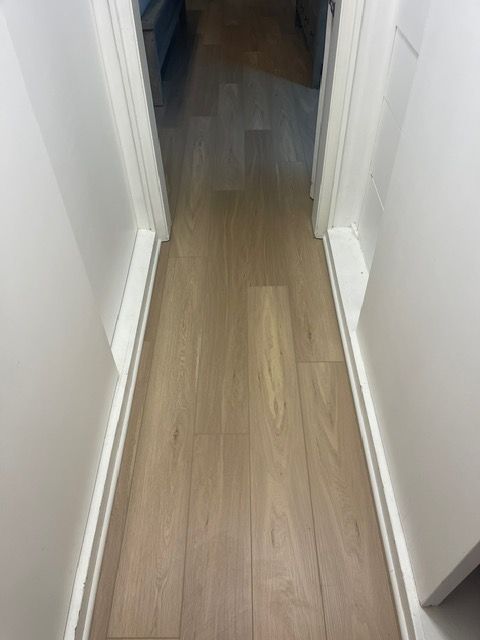 A hallway with a wooden floor and white walls.