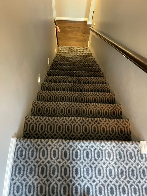 A set of stairs with a patterned carpet and a railing.