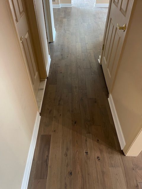 A hallway with hardwood floors and white trim in a house.