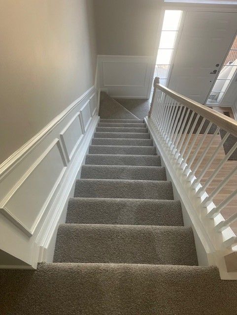 The stairs are carpeted and have a white railing.