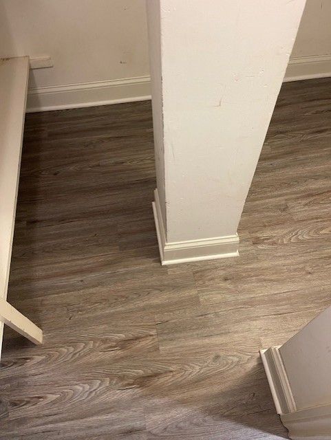 A wooden floor with a white pillar in a room.