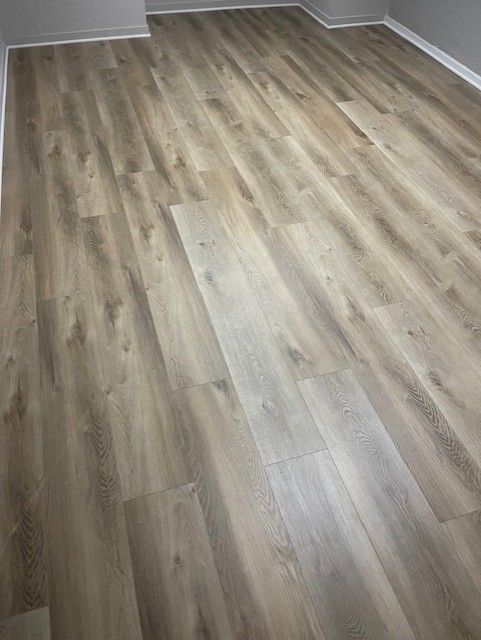 A room with a wooden floor and a gray wall.